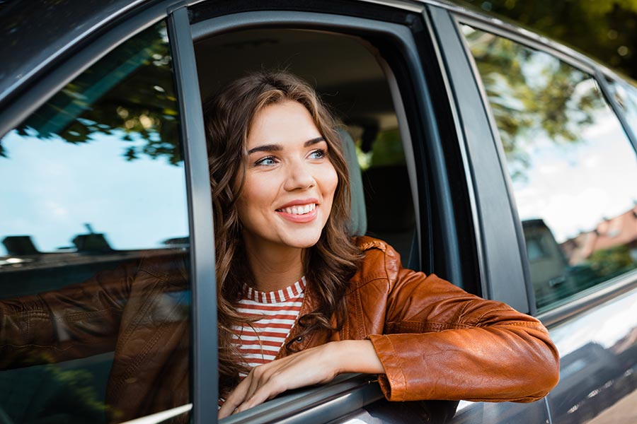 Client Center - Woman in Leather Jackets Looking Out Her Car Window and Smiling